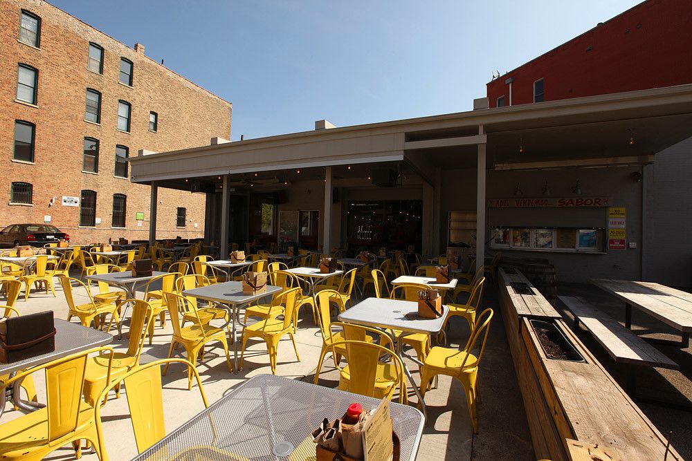 A bar’s patio filed with yellow metal chairs.