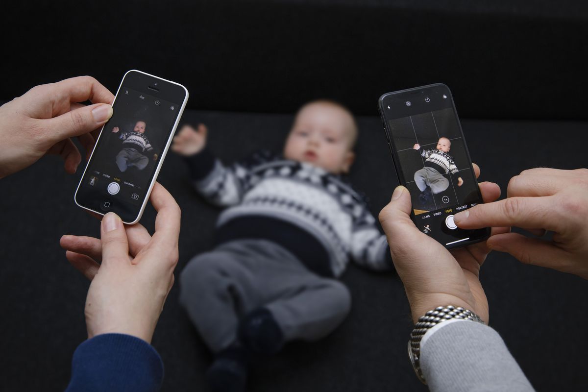 Adults hold their phones up to take a picture of a baby.