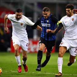 Mauro Icardi of FC Internazionale is challenged by Kostas Manolas and Federico Fazio both of AS Roma during the Serie A match between FC Internazionale and AS Roma at Stadio Giuseppe Meazza on January 21, 2018 in Milan, Italy.