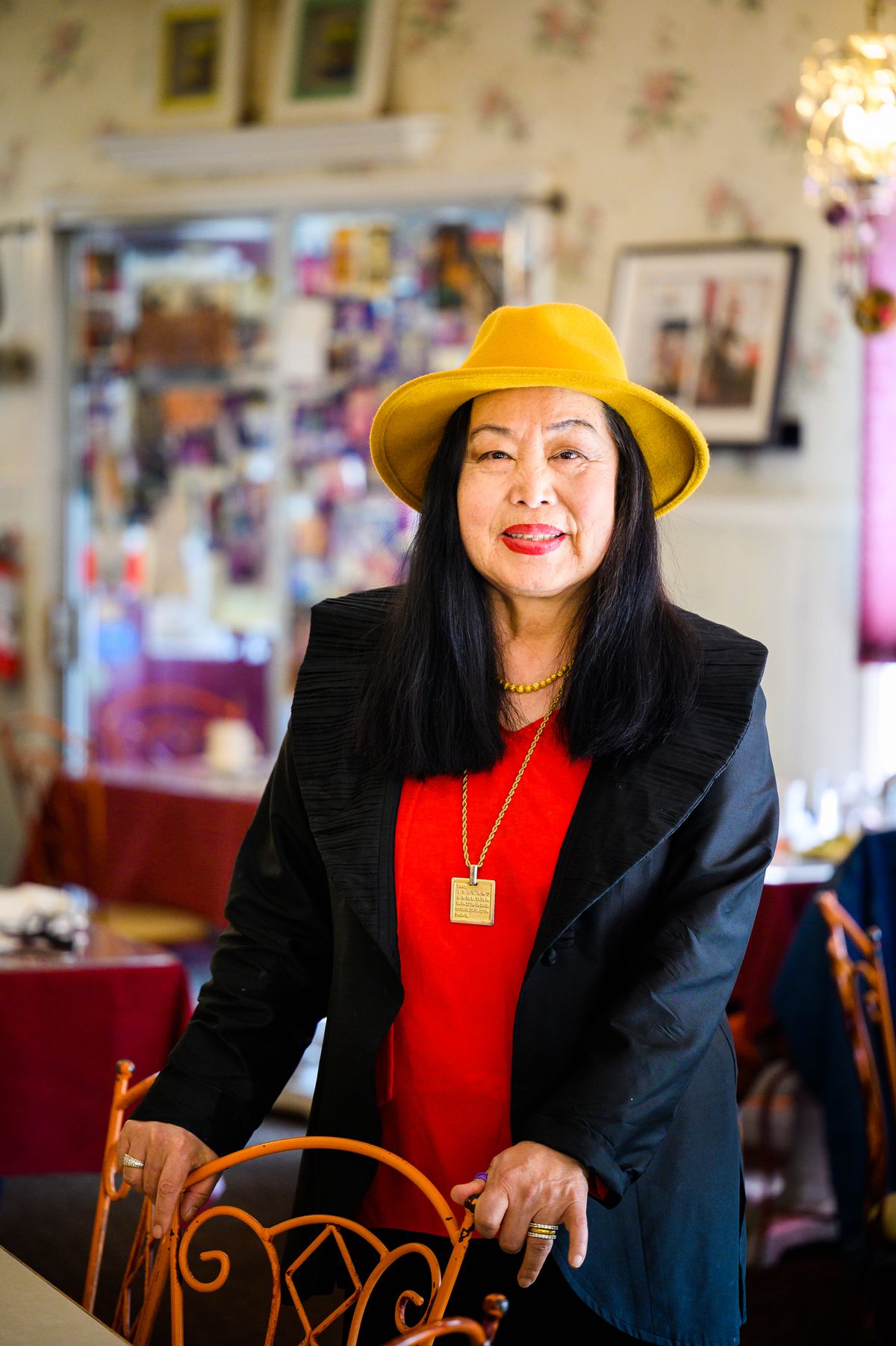 A woman in a red shirt and black jacket wearing a yellow hat.
