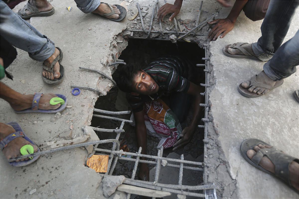 A Bangladeshi rescuer looks out from a hole cut in the concrete at the site of a building that collapsed Wednesday in Savar, near Dhaka, Bangladesh, Thursday, April 25, 2013. By Thursday, the death toll reached at least 194 people as rescuers continued to