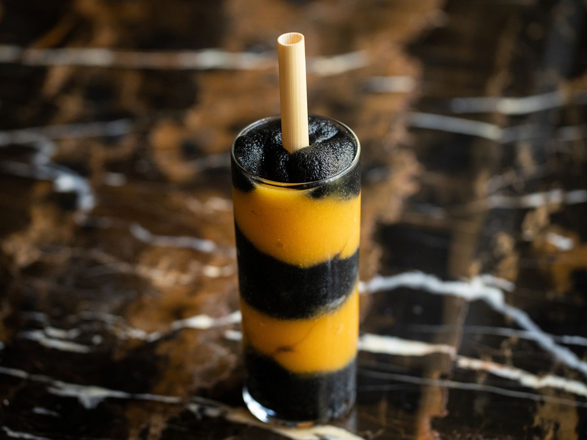 A frozen cocktail with alternating black and yellow parts of the drink layered in the glass