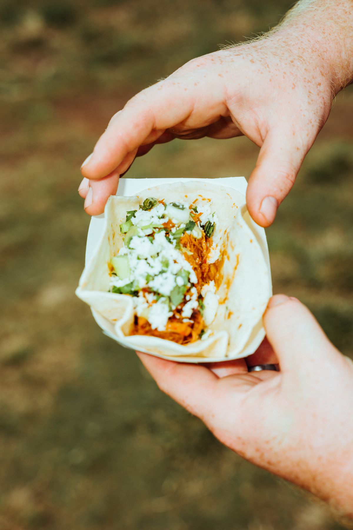 A hand holding up a taco in a tray.