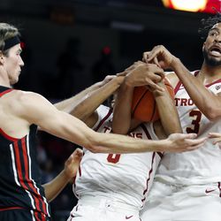 Southern California forward Isaiah Mobley, right, and center Lahat Thioune, center, vie for the ball against Utah center Branden Carlson, left, during the first half of an NCAA college basketball game in Los Angeles, Wednesday, Dec. 1, 2021. 