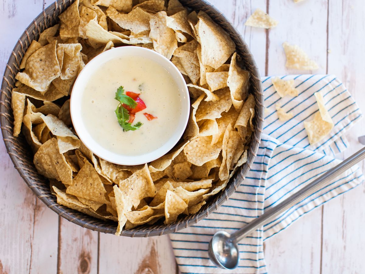 A bowl of queso in a tray of chips.