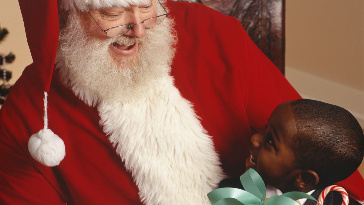 A Santa Claus looking at a smiling child on his lap.