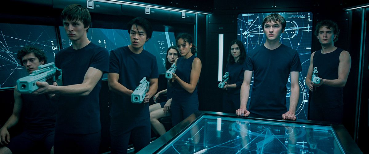 A group of rebellious space-teenagers in matching blue shirts, clutching futuristic plastic guns and standing in front of space-charts