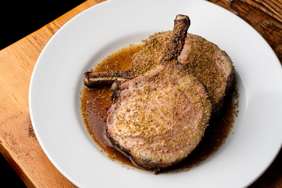 Two off-white pork chops sit atop each other on a white plate.