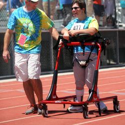 Chris Cook helps Faith Bogumil compete in the 25-meter assisted walk at the Special Olympics Utah 2013 Harmons Summer Games at Herriman High School in Herriman on Thursday, June 13, 2013.