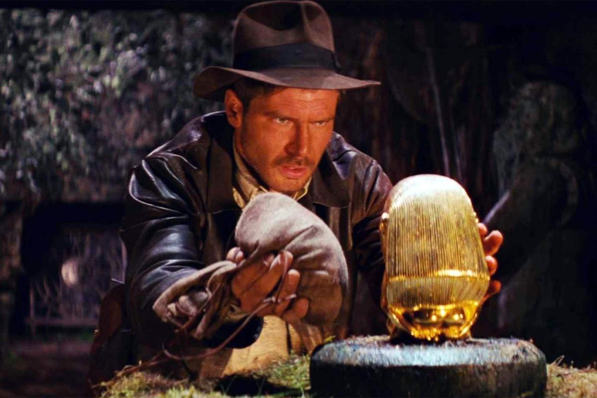 Harrison Ford as Indiana Jones removing an artifact from a pedestal in Raiders of the Lost Ark
