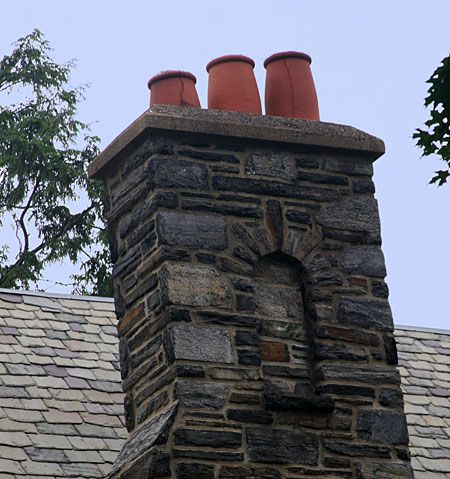 Stone chimney design with 3 clay pots on top.