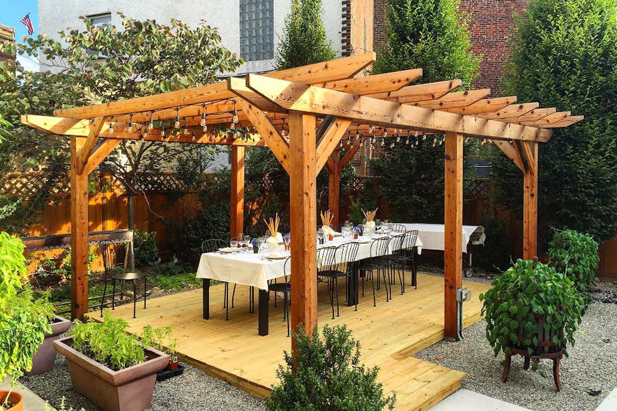 table set up under pergola surrounded by greenery