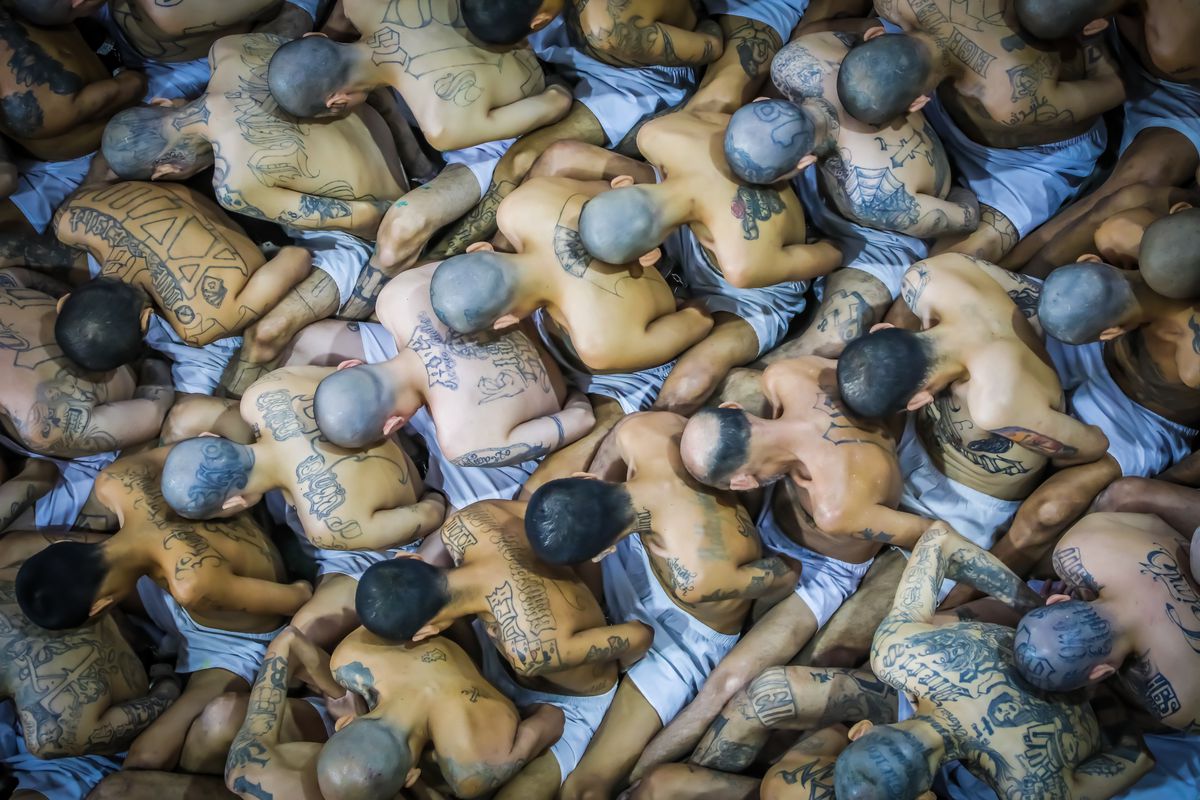 Shirtless inmates with tattoos, photographed from above. Extremely crowded conditions with bodies pressed against each other. 