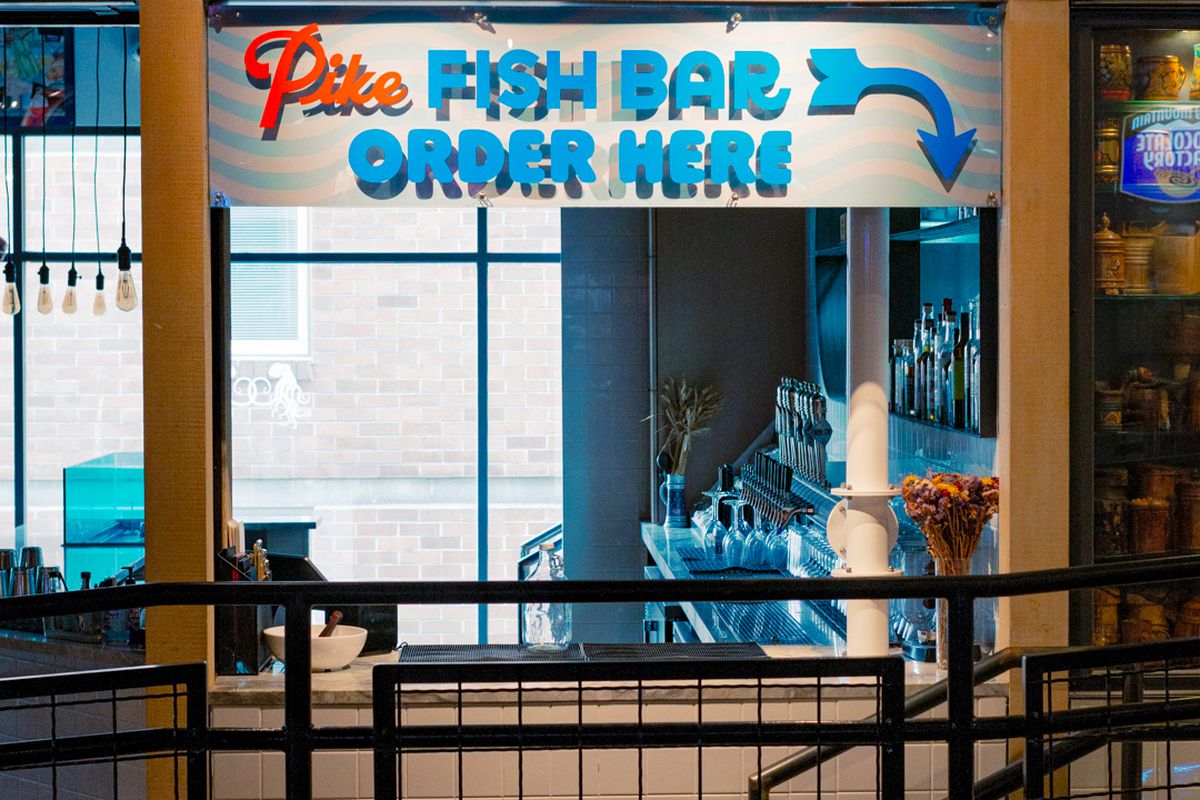 A takeout window with a sign above reading “Pike Fish Bar, order here.” 