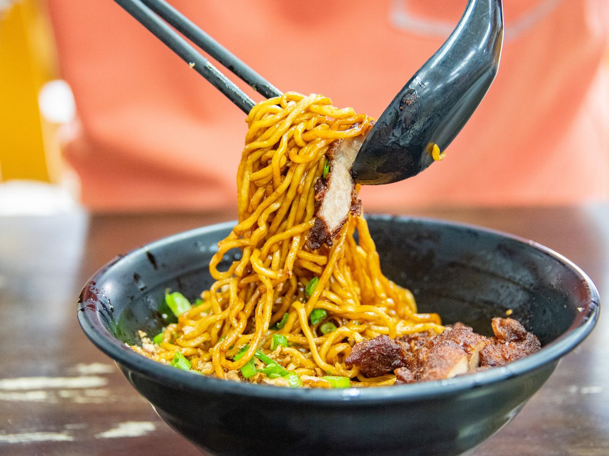 Chopsticks and a spoon hold up a scoop of chili pan mee
