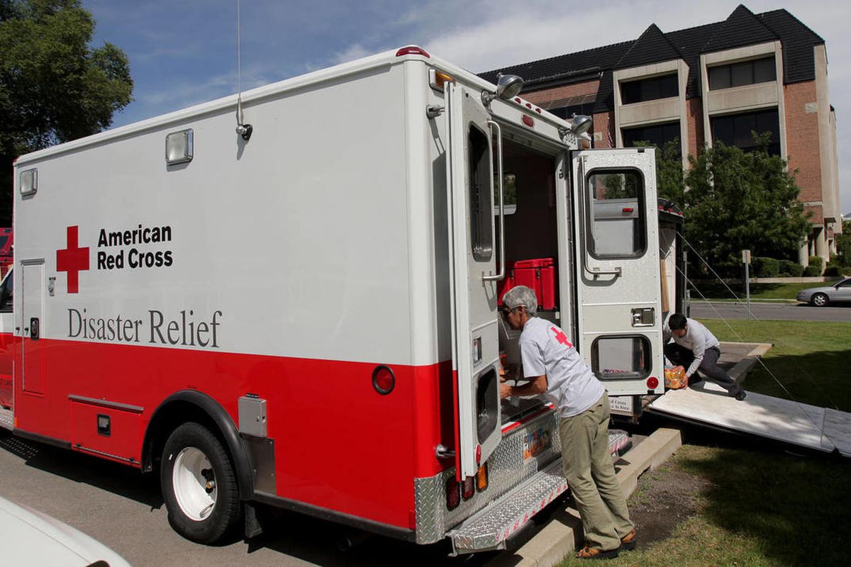 Red Cross workers load a Red Cross vehicle with supplies.
