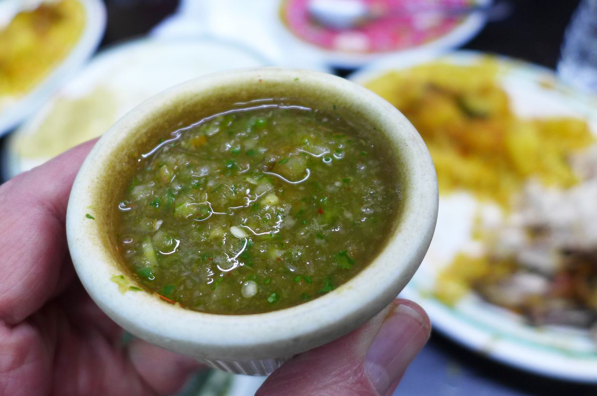 A small white crock filled with green cilantro hot sauce.