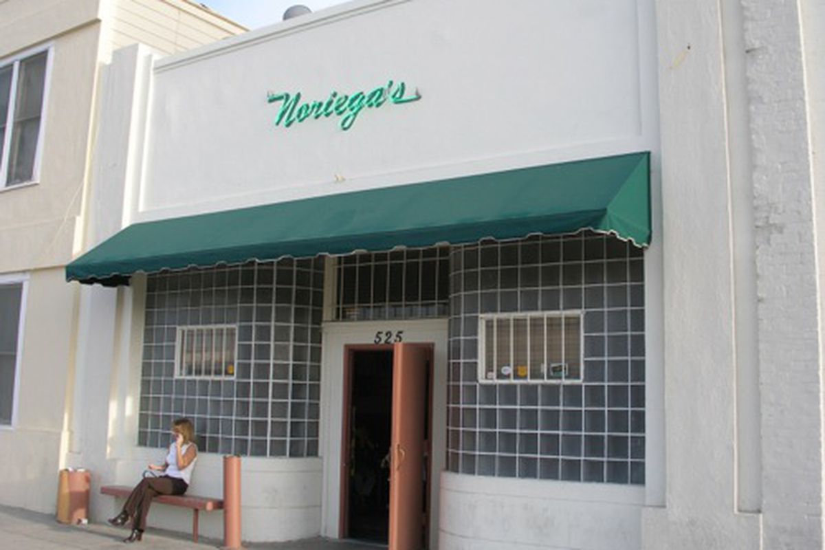 An exterior look at the old Basque restaurant Noriega Hotel, with green neon and white walls.