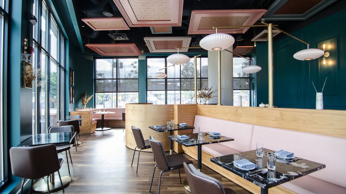 Interior of a classy but not too fancy restaurant with dark teal walls and pale pink booths.