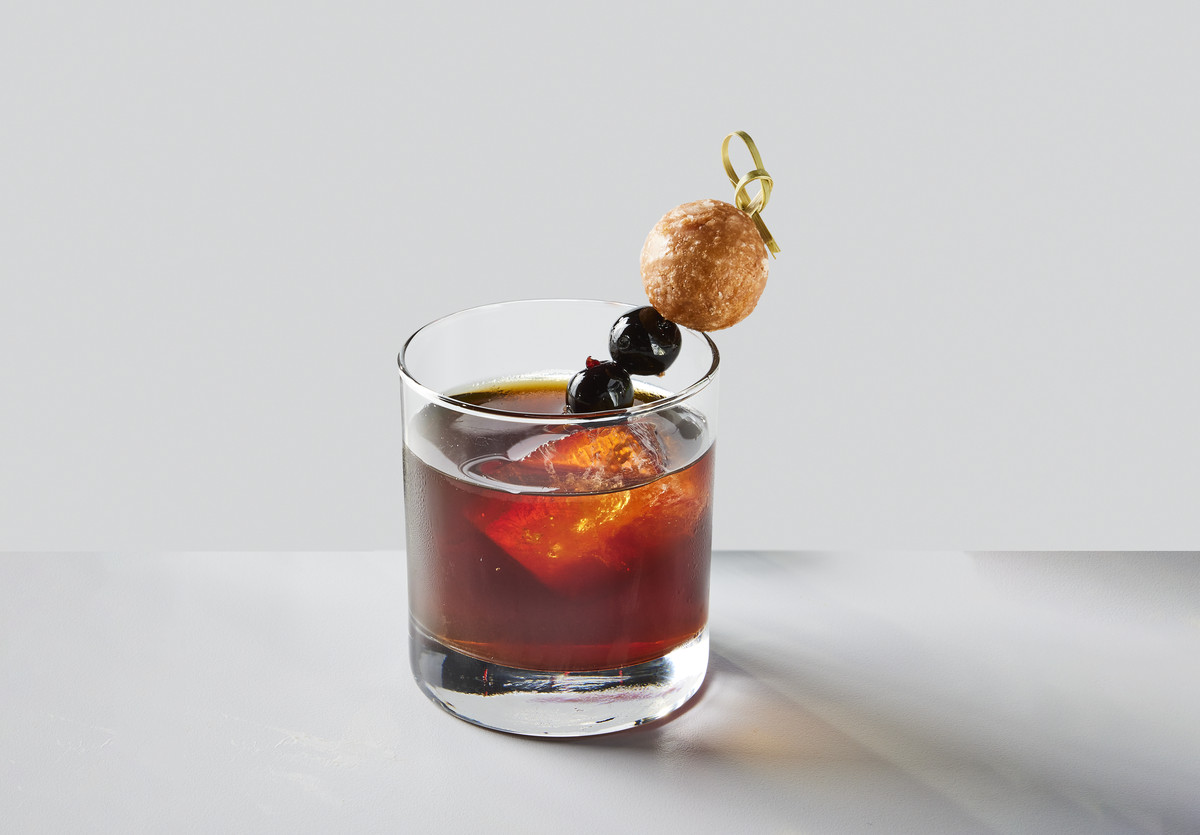 A cocktail with a doughnut hole garnish.