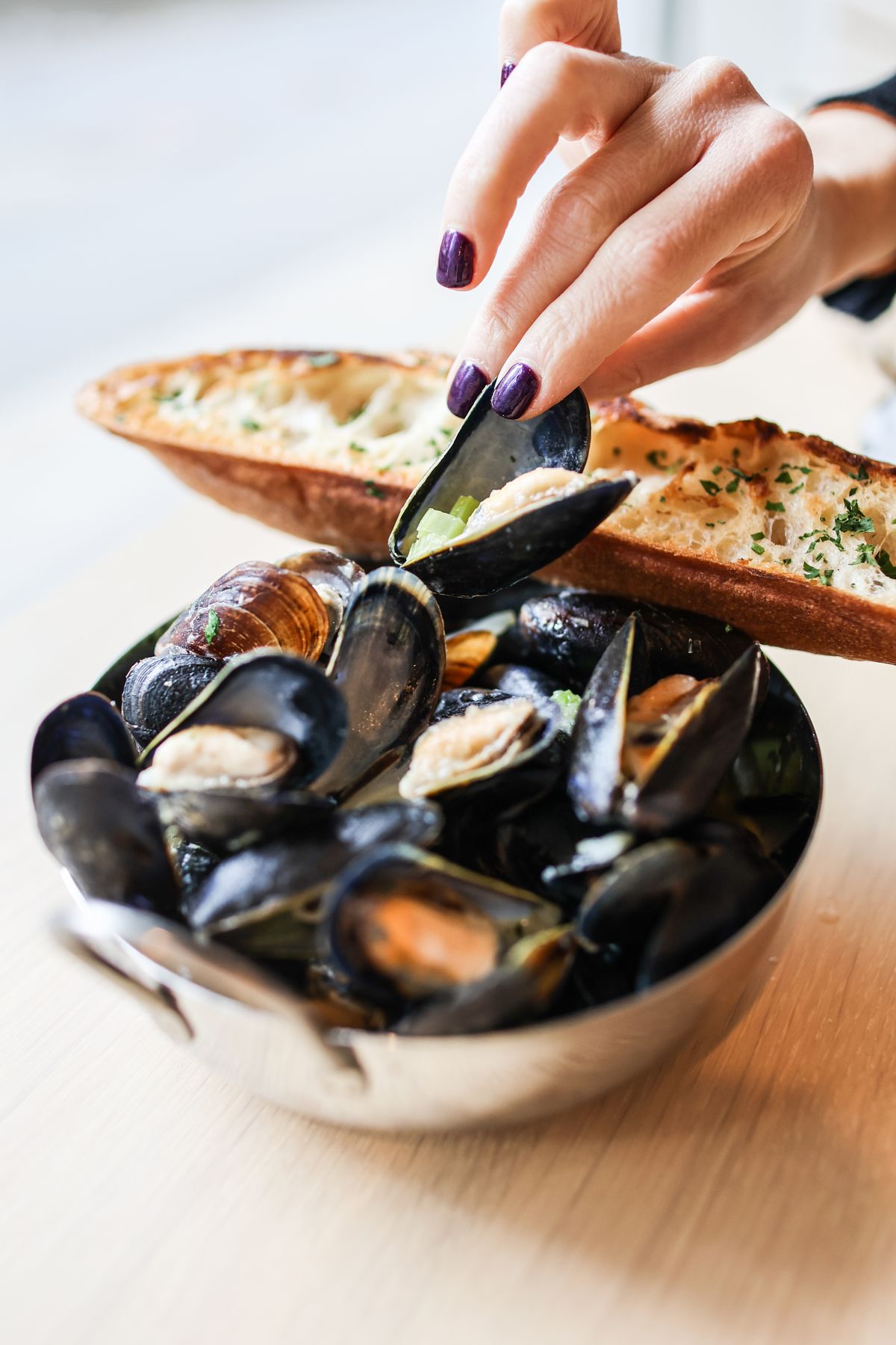 Mussels in a silver bowl next to a big baguette