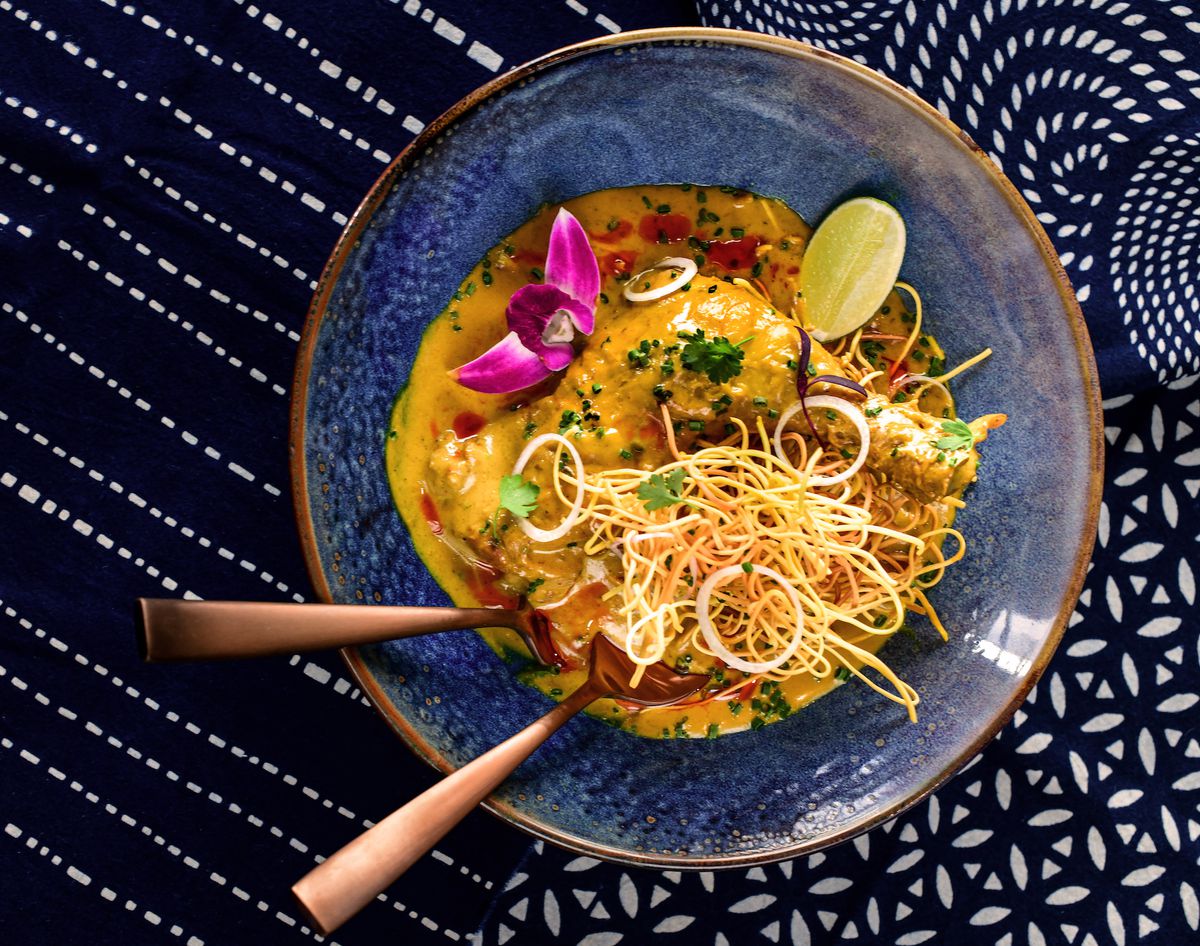 Chicken leg khao soi served in a blue stoneware bowl 