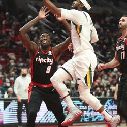 Utah Jazz guard Mike Conley jumps past Portland Trail Blazers forward Nassir Little during the first half of an NBA basketball game in Portland, Ore., Wednesday, Dec. 29, 2021. 