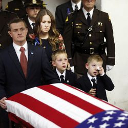 Janica Ellsworth, center, along with sons Bennett, left, and Ian, right, accompany the casket of their husband and father, Utah Highway Patrol trooper Eric Ellsworth, into the Dee Events Center in Ogden on Wednesday, Nov. 30, 2016.