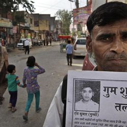In this Monday, March 25, 2013, photo, Kunwar Pal, 45, shows a poster of his missing son Ravi Kumar, 12, who went missing three years ago, in New Delhi, India. Kumar is among the more than 90,000 children who go missing in India each year. More than 34,000 of them are never found, the government said last year. (AP Photo/Manish Swarup)