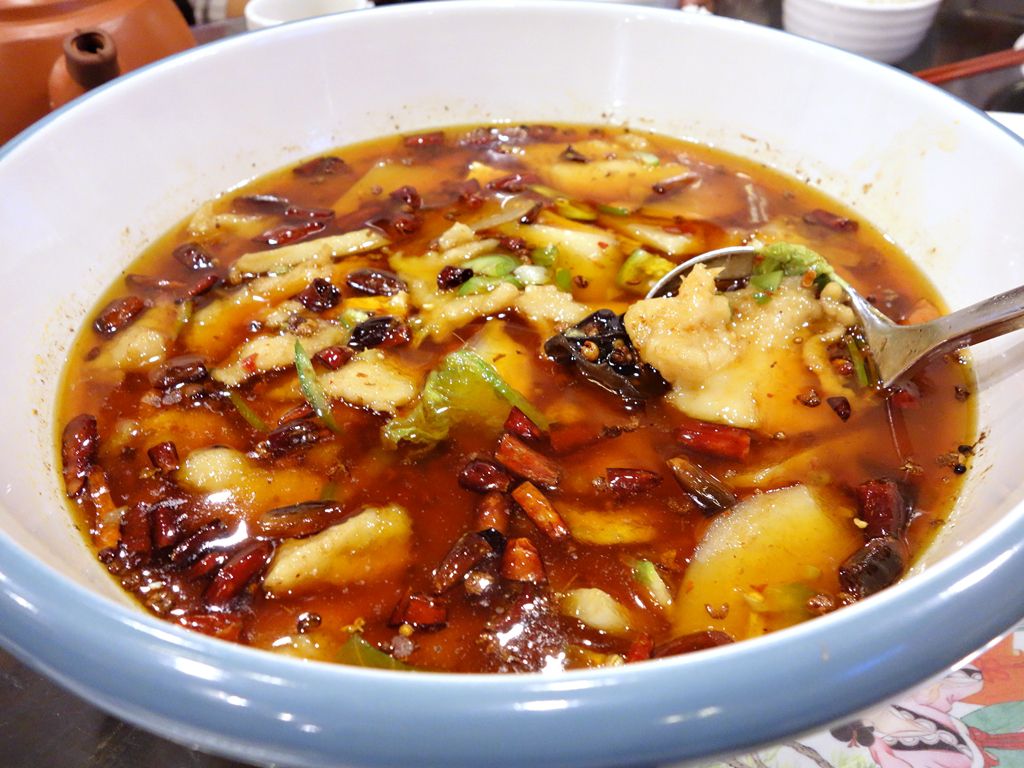 A bowl of red broth with fish at Silkway Halal Cuisine.