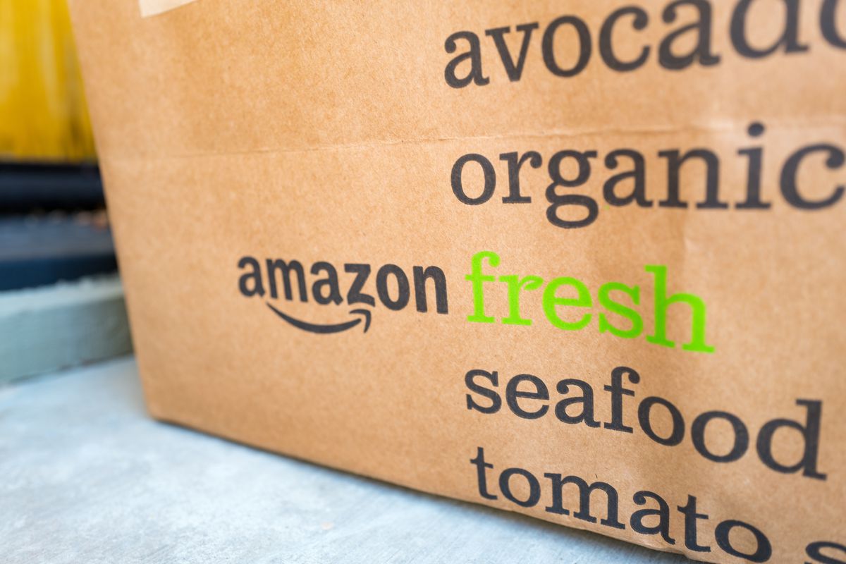 Brown paper tote for Amazon Fresh grocery delivery service, with Amazon logo and text listing groceries which may be ordered using the service