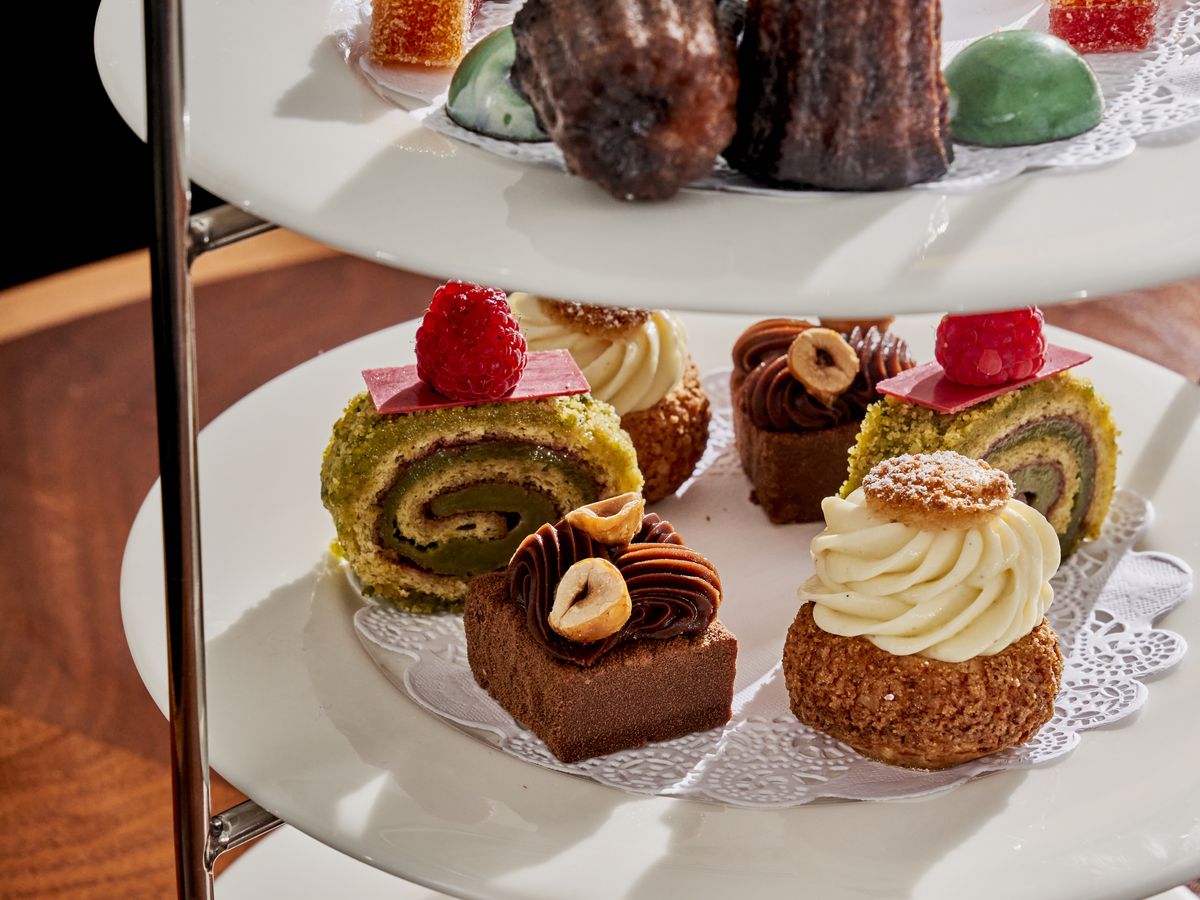 Caneles, pate de fruits, a frozen souffle, and a tart sits on three plates stacked vertically
