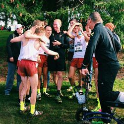Davis cross country coach Corbin Talley, center in black, was honored with the Nike boys Coach of the Year award. He celebrates here with his team after the Darts finished fourth overall Saturday.