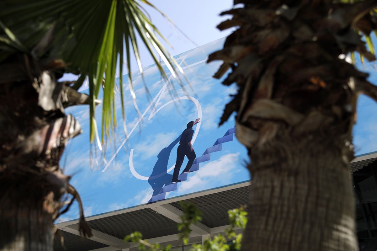A billboard seen between palm trees.