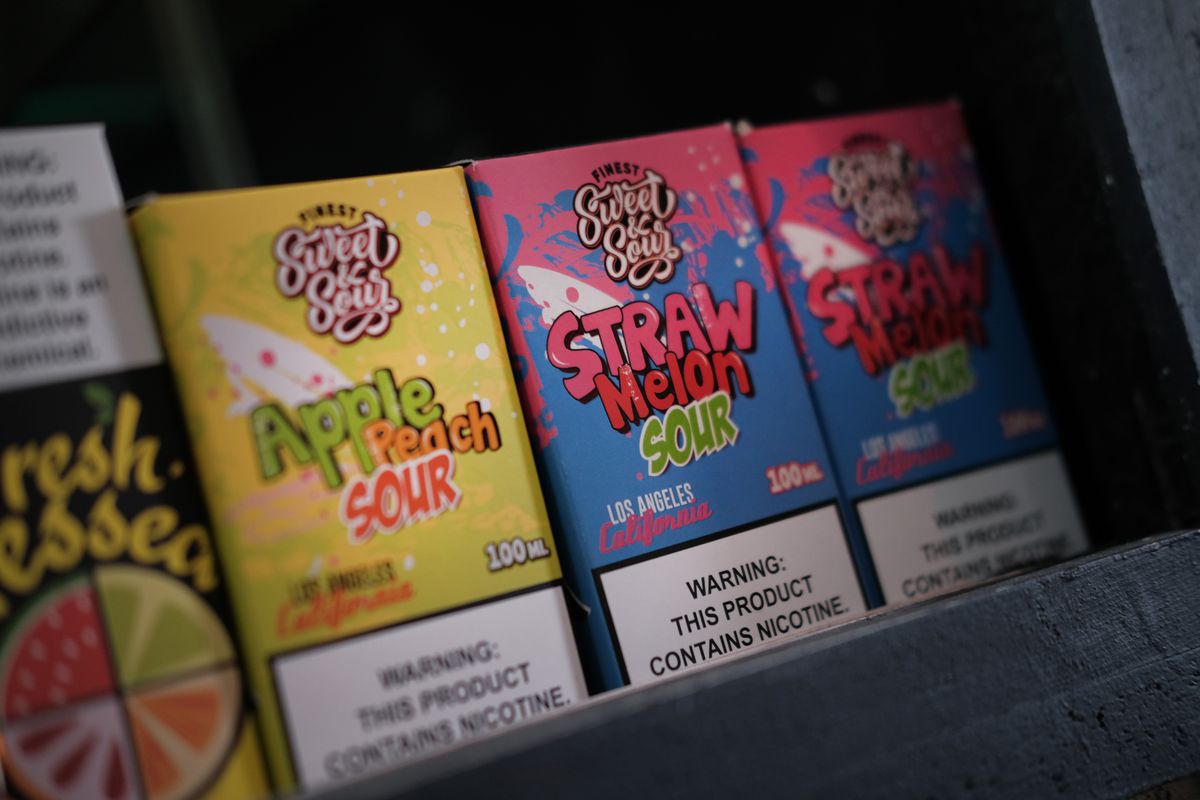 Fruit-flavored vape products on a shelf in a vape store.