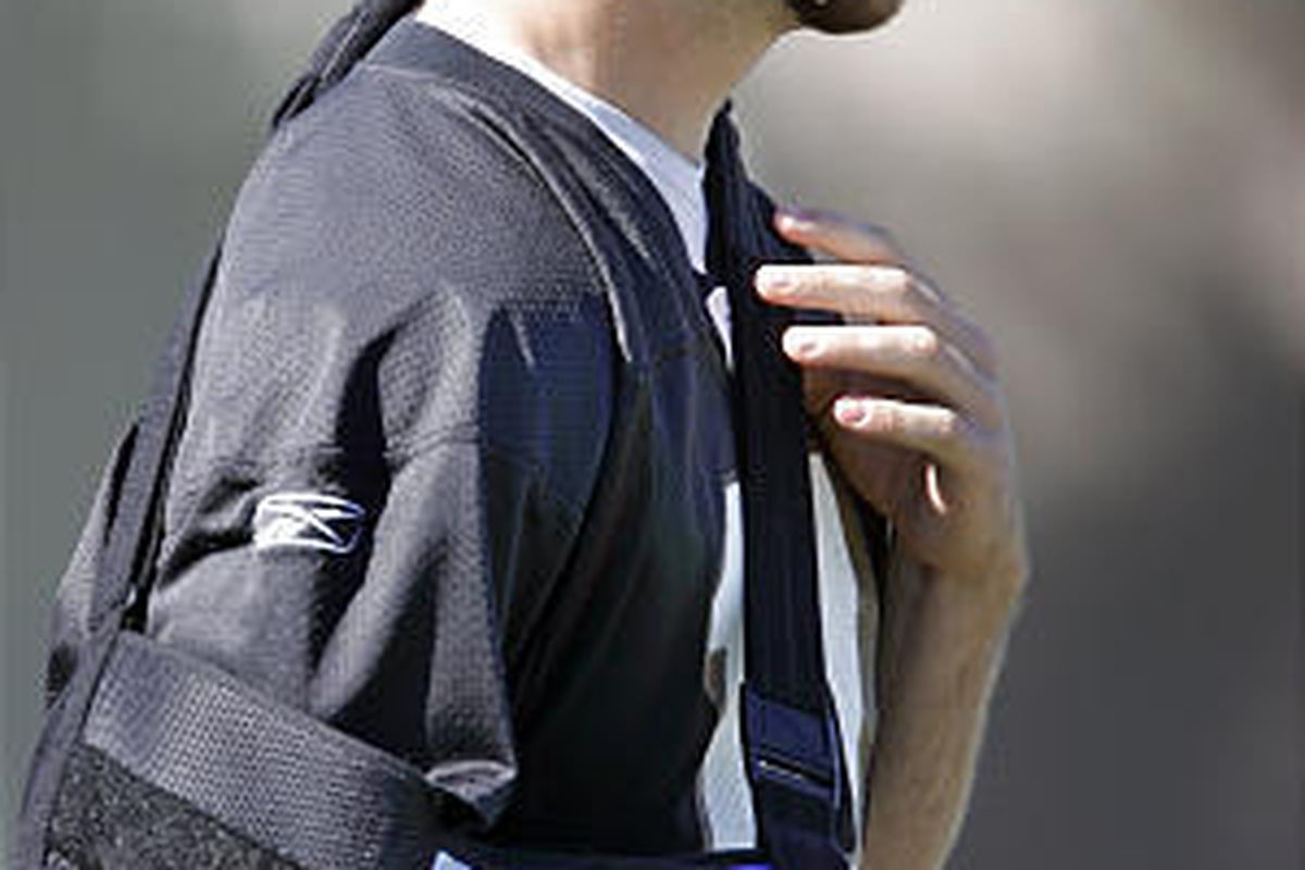 Injured San Francisco 49ers quarterback Alex Smith wears a sling as he watches practice.