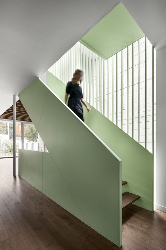Woman walking down sage green stairs.