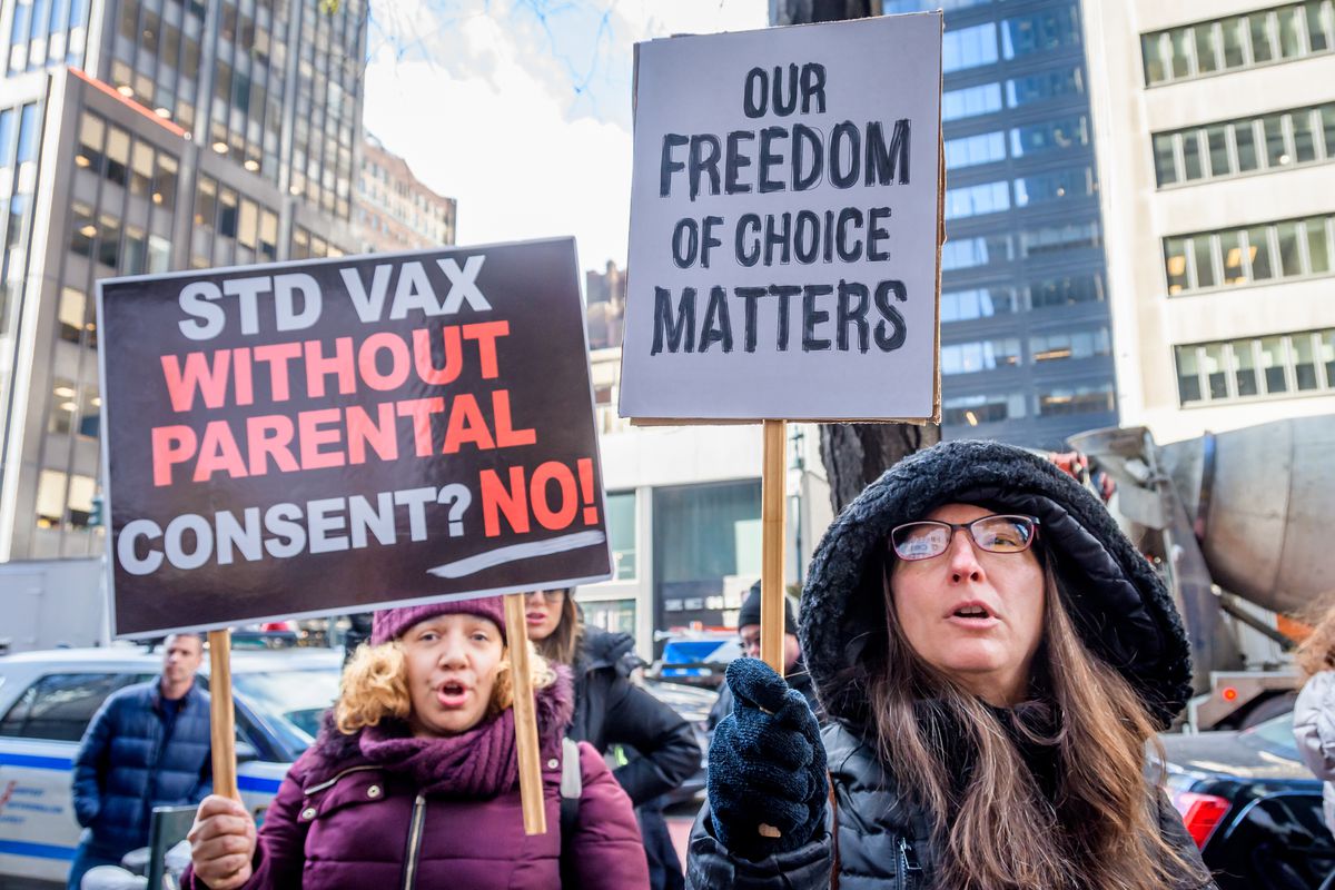 Protestors hold signs at a rally against the HPV vaccine. Their signs read “STD Vax without parental consent? No!” and “Our freedom of choice matters.”