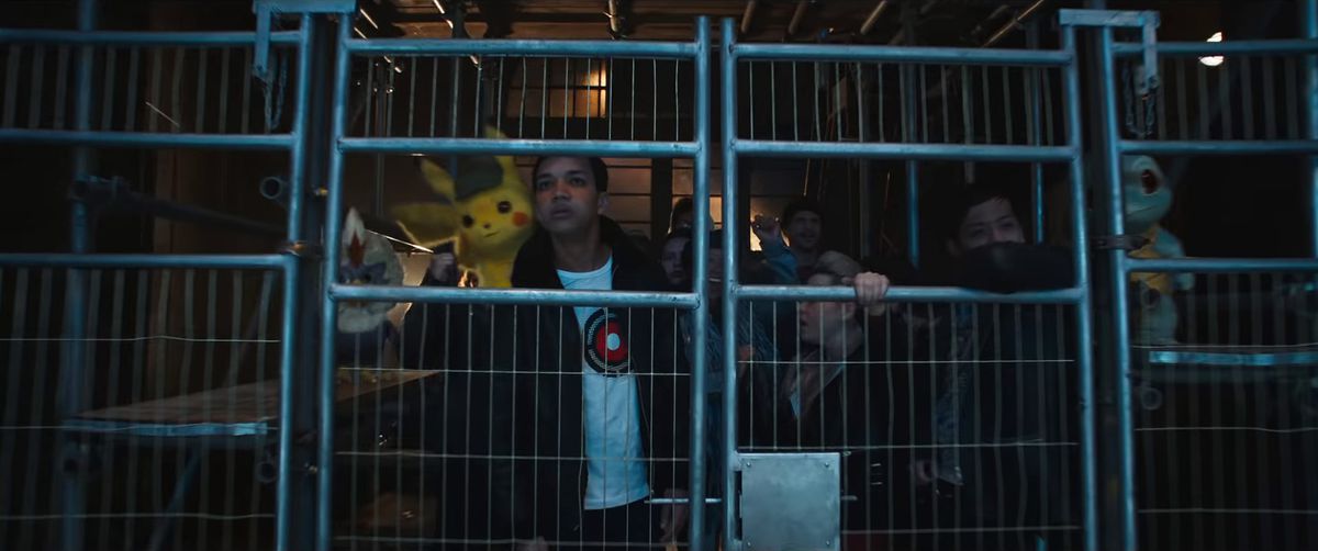 Detective Pikachu - Tim, Pikachu, a Squirtle and a bunch of other people behind a fence