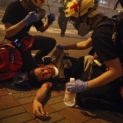 Medical workers help a protester in pain from tear gas fired by policemen on a street in Hong Kong, Sunday, July 21, 2019. Hong Kong police have thrown tear gas canisters at protesters after they refused to disperse. Hundreds of thousands of people took part in a march Sunday to call for direct elections and an independent investigation into police tactics used during earlier pro-democracy demonstrations. Police waved a black warning flag Sunday night before lobbing the canisters into a crowd of protesters. (AP Photo/Bobby Yip)