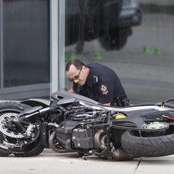 A police officer examines a motorcycle after a female stunt driver working on the movie "Deadpool 2" died after a crash on set, in Vancouver, B.C., on Monday Aug. 14, 2017. Vancouver police say the driver was on a motorcycle when the crash occurred on the movie set on Monday morning.