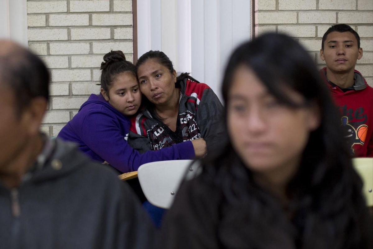 In this Jan. 5, 2016 photo, Central American migrants embrace as they wait for assistance at a center for newly-arrived migrant families with children, at Sacred Heart Catholic Church in McAllen, Texas. Assistance includes clothes, a meal, a shower and ac