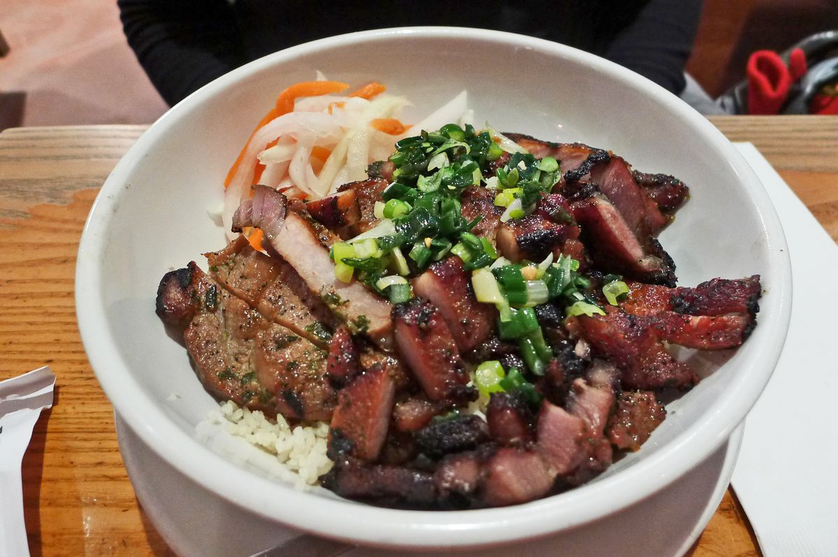 A bowl filled with grilled meat, with shredded carrots and daikon on the side.