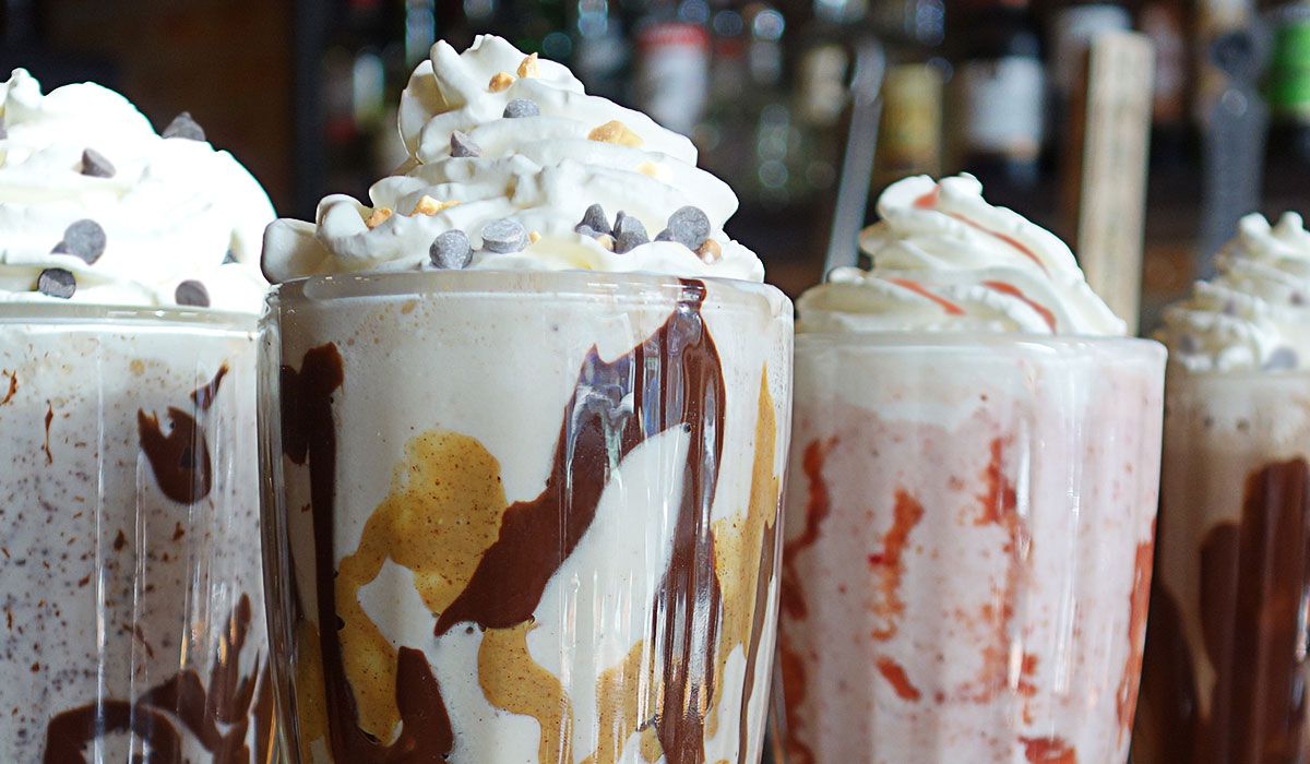 Four milkshakes with whipped cream in glasses
