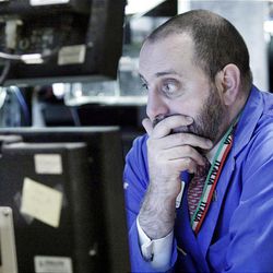Specialist Peter Giacchi studies his screens as he works at his post on the floor of the New York Stock Exchange Thursday.