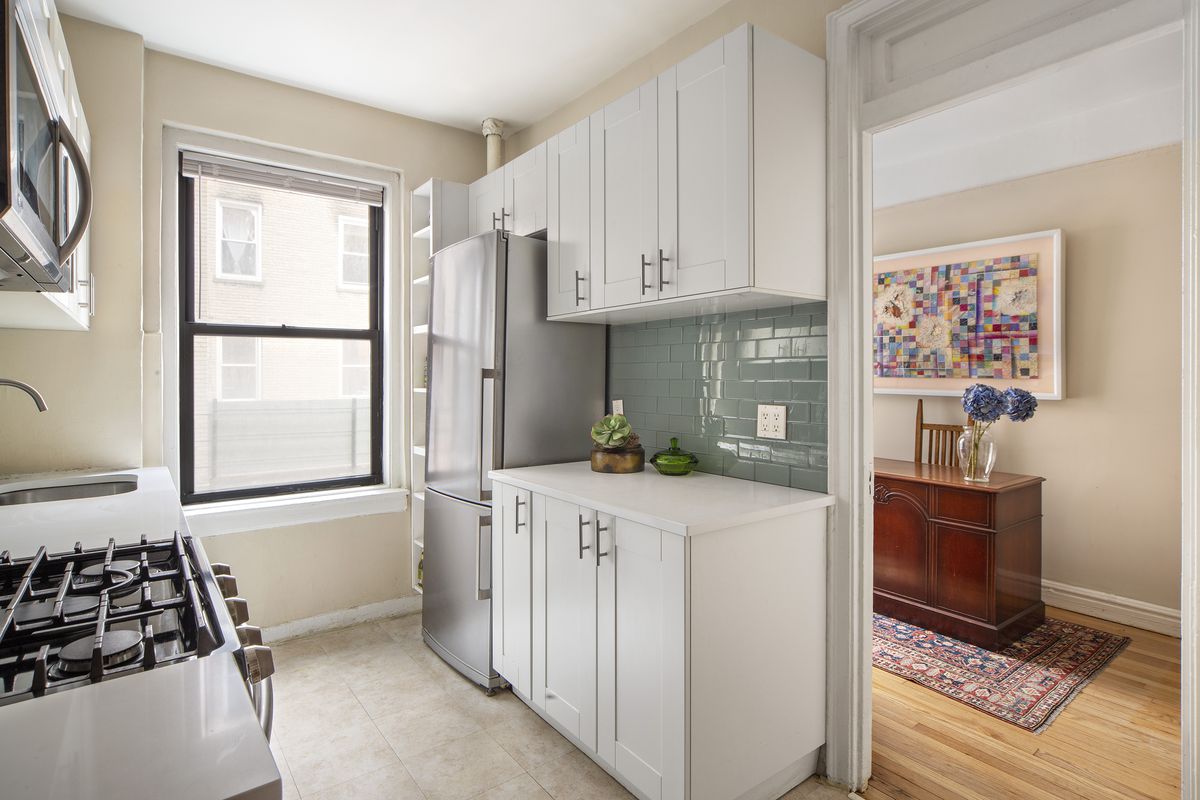 A small kitchen with a window and white cabinetry.