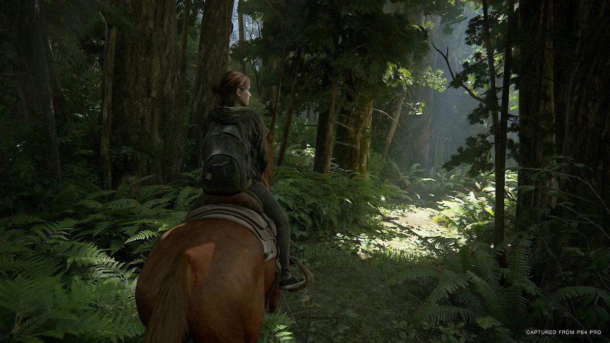 Ellie rides a horse through a forest in a screenshot from The Last of Us Part 2