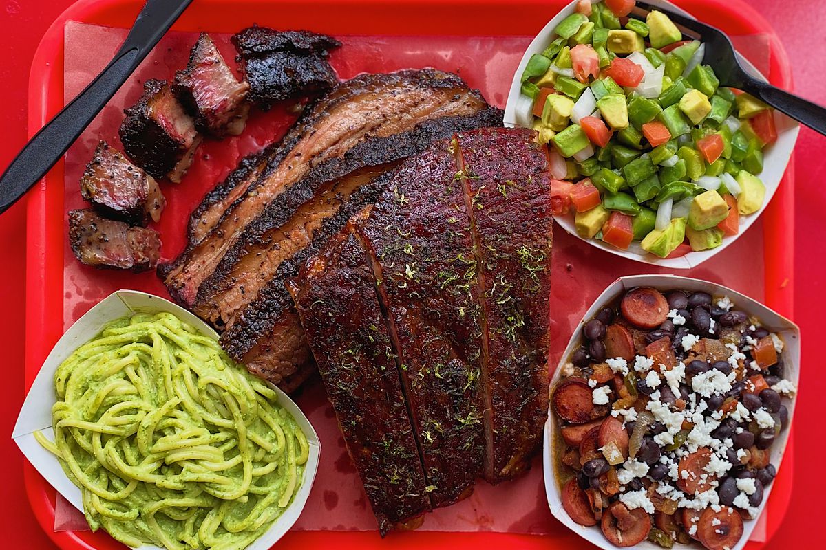A red tray of barbecued meats and sides.