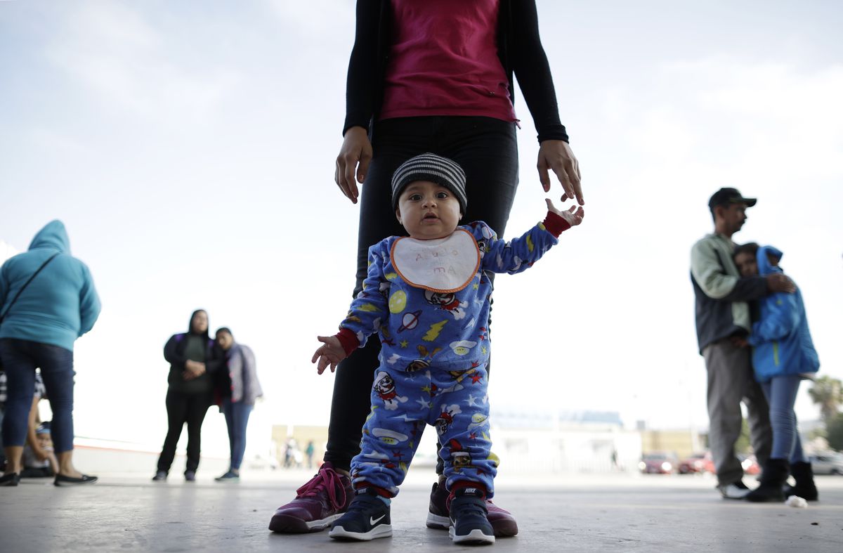 In this June 13, 2018 photo, nine month-old Jesus Alberto Lopez, center, stands with his mother, Perla Murillo, as they wait with other families to request political asylum in the United States, across the border in Tijuana, Mexico. The family, from the M