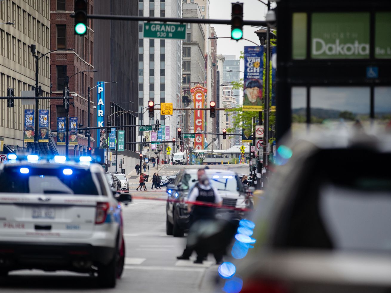 Police cars are parked near West Grand Avenue and North State Street in the River North neighborhood after three people were shot Saturday in a parking garage in the first block of West Grand Avenue, according to Chicago police.